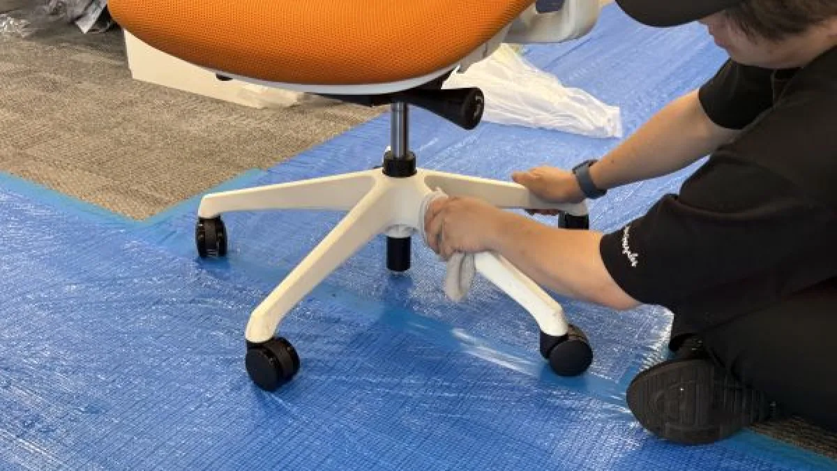 オフィスチェアの脚部とキャスターを磨いている様子